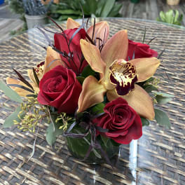 Red roses and orchids arranged in a glass vase