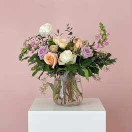 Mixed roses and lavender flowers in a clear glass vase