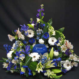 Blue and white floral arrangement with a blue glass candle holder in the center