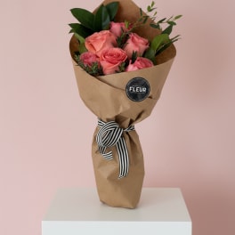 Bouquet of pink roses wrapped in brown paper with a striped ribbon