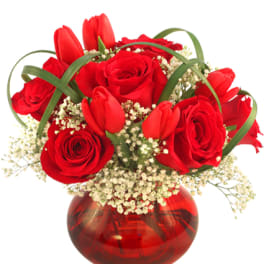 Red roses and tulips in a red glass vase