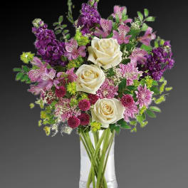 Bouquet of white roses, purple flowers, and pink blooms in a clear vase