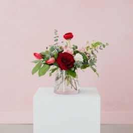 Red roses and pink tulips in a clear glass vase