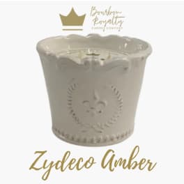 Cream ceramic candle jar with a scalloped rim and gold logo text