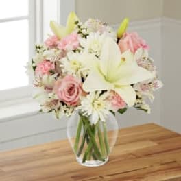 Pink and white bouquet with lilies and roses in a clear glass vase