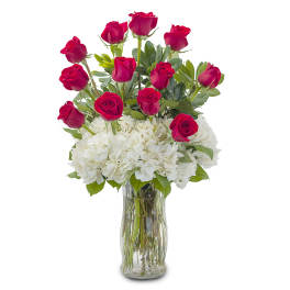 Red roses arranged with white hydrangeas in a clear glass vase