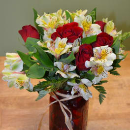 Red roses and white alstroemeria in a red glass vase