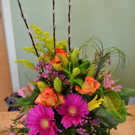Mixed bouquet in a green vase with pink daisies, roses, and lilies
