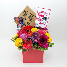 Colorful mixed flower arrangement in a red box with a card and butterfly decoration