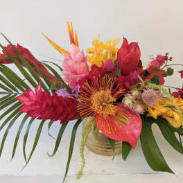 Tropical bouquet with red, pink, and yellow flowers in a gold vase