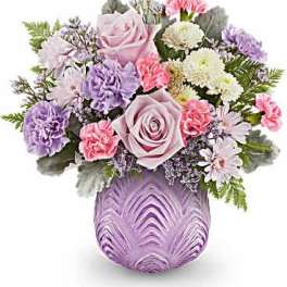 Lavender and pink floral arrangement in a purple glass vase