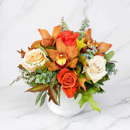 Orange and white roses with orchids in a white vase