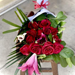Bouquet of red roses with pink lilies and greenery wrapped in paper