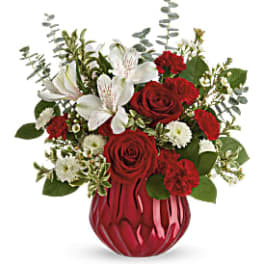 Red roses and white lilies arranged in a red glass vase