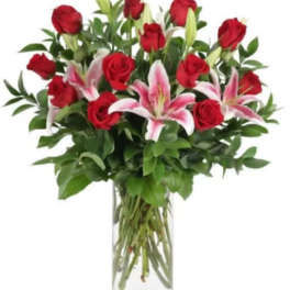 Tall clear vase with red roses and pink lilies arranged in a lush, upright bouquet
