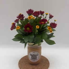 Bouquet of burgundy and yellow flowers in a glass jar