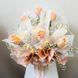 Peach roses with baby's breath and ribbon in a wrapped bouquet