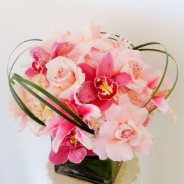Pink roses and orchids arranged in a square vase