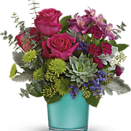 Pink roses and purple flowers in a turquoise glass vase