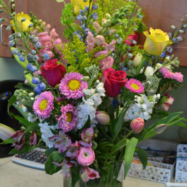Mixed bouquet of roses, daisies, and snapdragons in a glass vase
