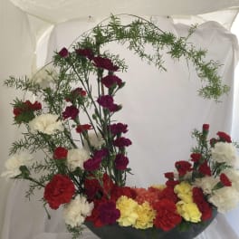 Carnation arrangement with red, white, yellow, and magenta blooms in a bowl vase