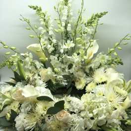 White floral arrangement with calla lilies, roses, orchids, and chrysanthemums