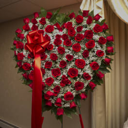 Heart-shaped red rose arrangement with a large red bow