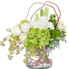White lilies and roses in a glass vase with green hydrangea