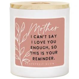 White candle in a glass jar with a pink Mother label and gold lid