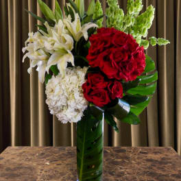 Red roses and white lilies arranged in a tall glass vase