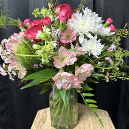 Mixed pink and white flowers arranged in a glass vase