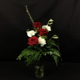 Red and white roses in a clear glass vase with greenery