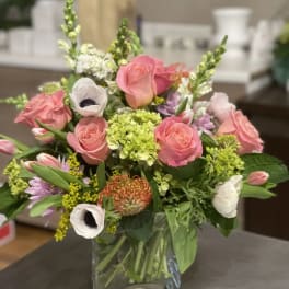 Pink roses and mixed blooms arranged in a clear glass vase