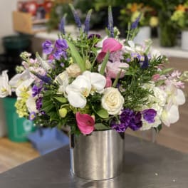 Mixed bouquet of white, pink, and purple flowers in a silver vase