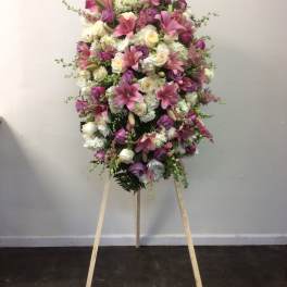Large pink and white funeral spray on a wooden easel