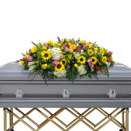 Colorful floral casket spray with sunflowers, roses, and white blooms