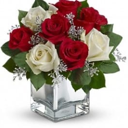 Red and white roses in a clear square vase