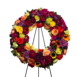 Circular floral wreath on a black easel with multicolored blooms
