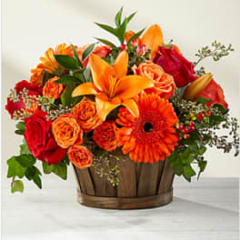 Orange and red mixed flower arrangement in a wooden basket