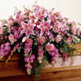 Pink floral spray arranged on a wooden casket