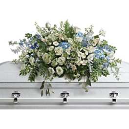 White and blue floral casket spray on a silver casket