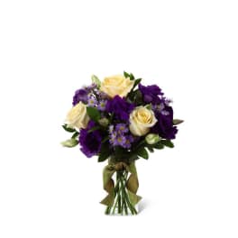 Small vase arrangement of cream roses, purple lisianthus, and lavender asters in a ribboned glass vase.