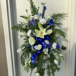 Tall floral standing spray with white and blue flowers on an easel
