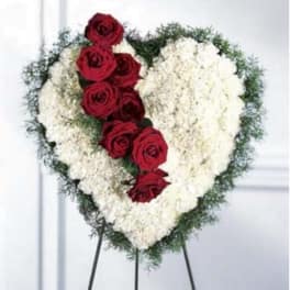 Heart-shaped floral spray with red roses and white flowers on an easel