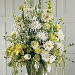 Tall green and white floral arrangement in a ribbed vase