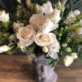 Bouquet of pale peach roses and white blooms in a gray vase