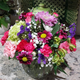 Mixed bouquet in a clear glass vase with pink, purple, white, and green flowers