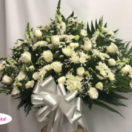 White floral spray with roses and daisies, finished with a silver bow