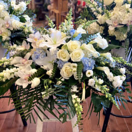 White floral casket spray with roses, lilies, and orchids