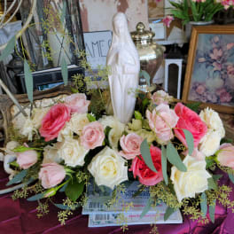 Pink and white roses arranged around a white statue